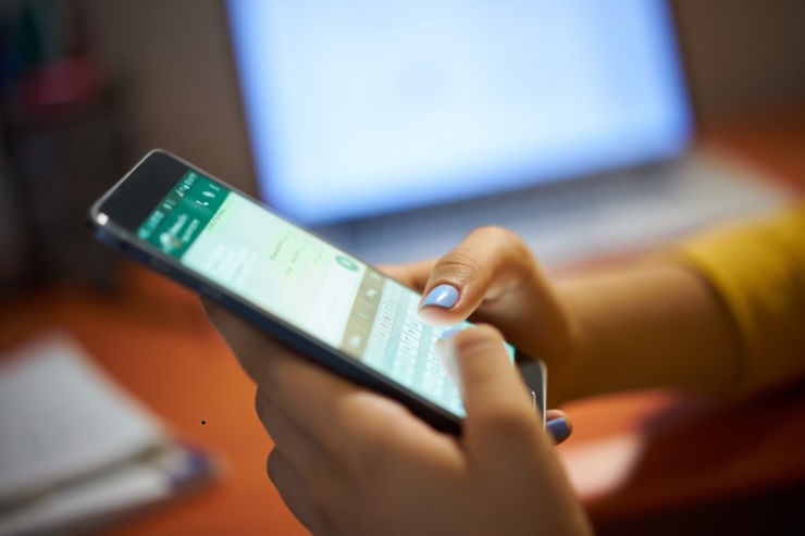 mani di donna con maglione giallo che scrivono su smartphone su whatsapp 