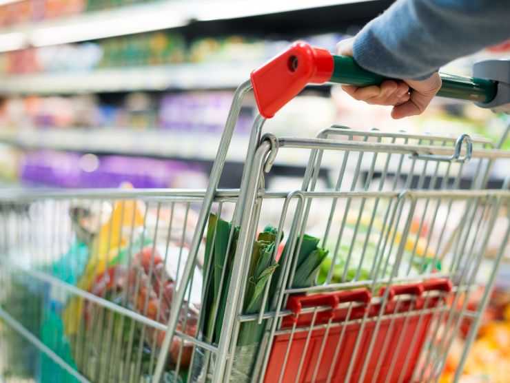 donna che guida carrello con spesa al supermercato