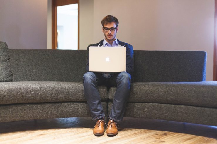 ragazzo seduto sul divano con il computer sulle gambe