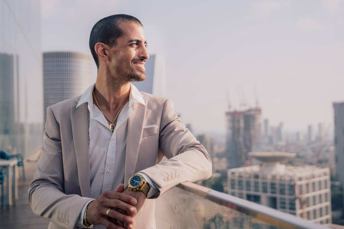 uomo vestito elegante con orologio d'oro su una terrazza che guarda la città 