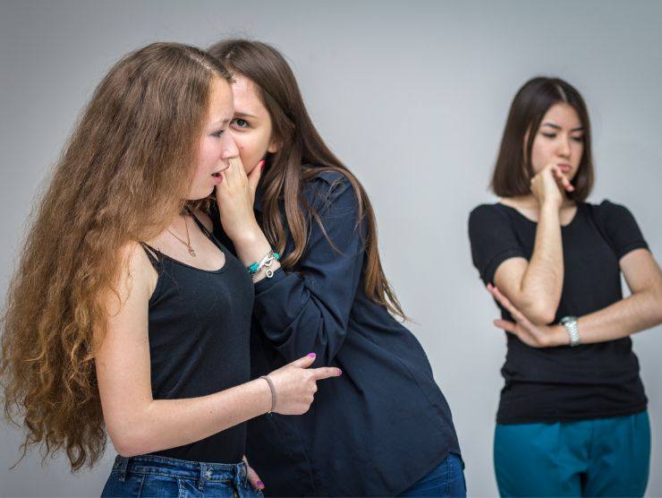 ragazze che sparlando di una terza ragazza che guarda