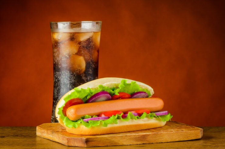 panino hot dog con wurstel, pomodoro e insalata e bicchiere di coca cola con ghiaccio