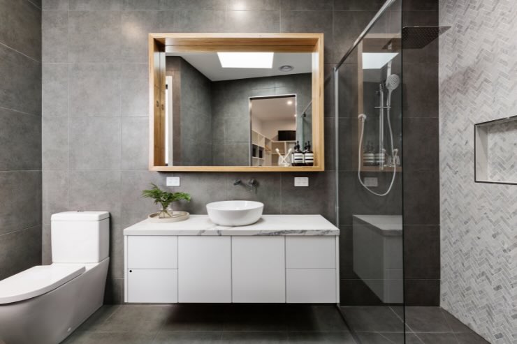 bagno con specchio di legno, mobile e wc bagno, rivestimento grigio