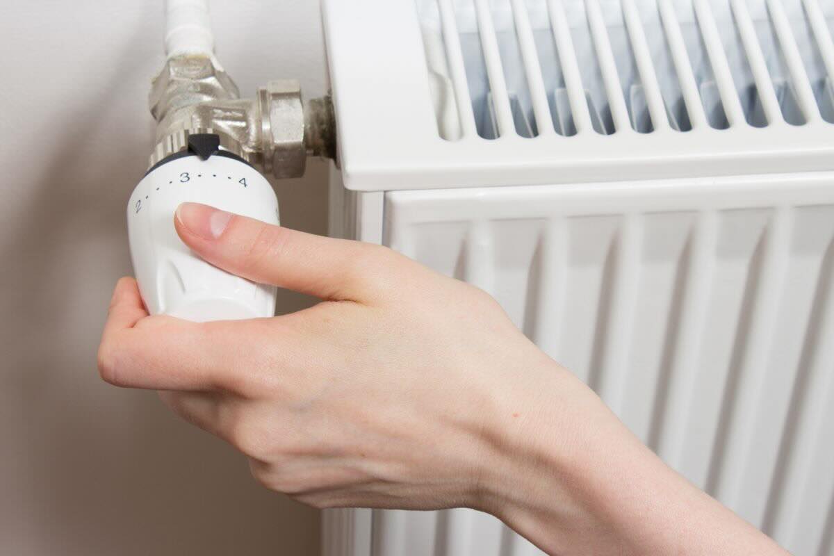 Mano di donna che gira la manipola del termosifone