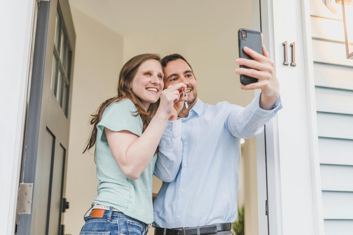 coppia che si fa un selfie sulla porta di casa mostrando le chiavi