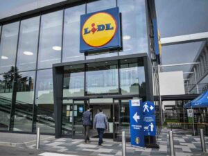 Supermercato con insegna Lidl facciata di vetro, due uomini che si accingono ad entrare dentro