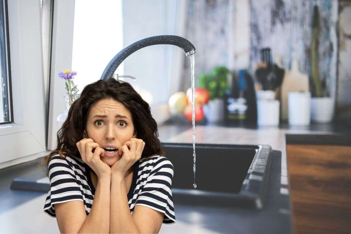 donna spaventata e rubinetto in cucina aperto